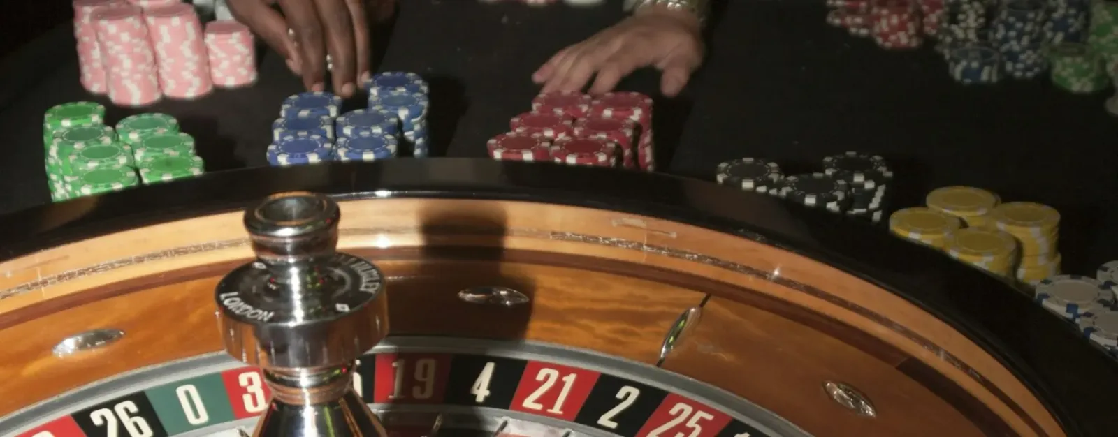 Primer plano de una rueda de ruleta en movimiento con fichas apiladas al costado del paño.